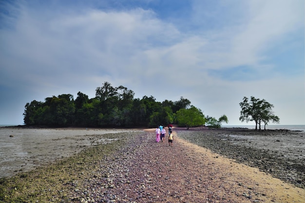 Un groupe de personnes marchant vers une île unique à marée basse sur le détroit de Malacca