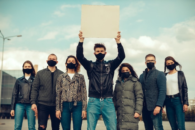 Un groupe de personnes avec masque et affiches pour protester contre la protestation de la population contre le coronavirus