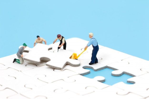 Groupe de personnes miniatures assemblant un puzzle. Concept de travail d&#39;équipe commercial.