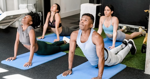 Groupe de personnes multiethniques faisant des exercices d'étirement sur des tapis