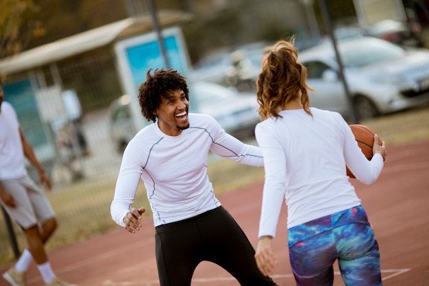 Groupe de personnes multiethniques jouant au basketball sur le court