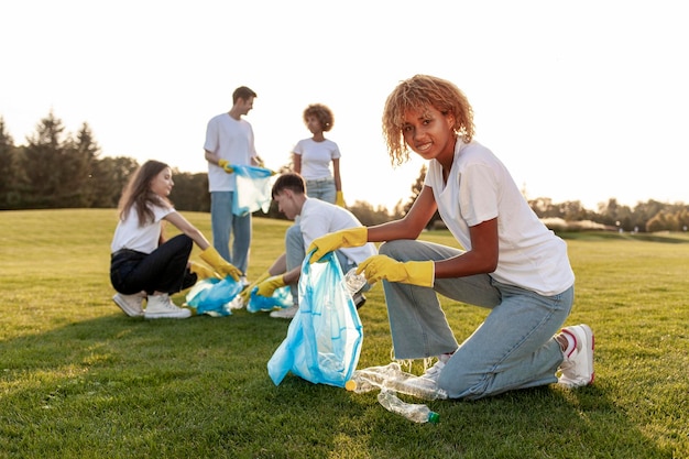 un groupe de personnes multiraciales en gants et avec des sacs à ordures enlèvent le plastique et les ordures dans le parc