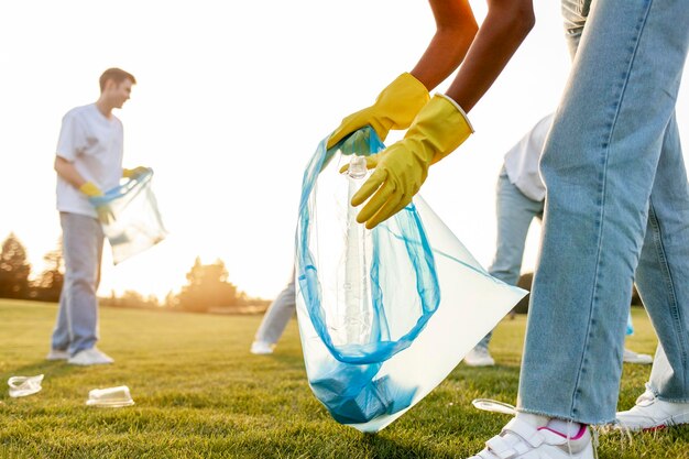 Photo un groupe de personnes multiraciales en gants et avec des sacs à ordures enlèvent le plastique et les ordures dans le parc