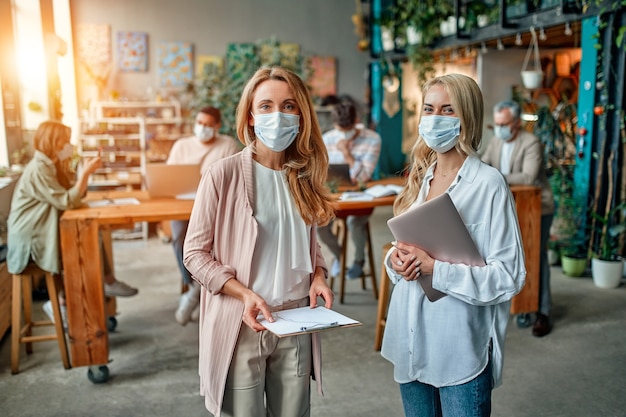 Groupe de personnes multiraciales travaillant dans un bureau moderne pendant le coronavirus. Les jeunes gens d'affaires et le patron senior travaillent ensemble en portant des masques de protection du visage. Mesures préventives pendant le Covid-19