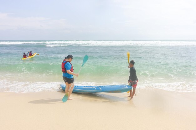 Un groupe de personnes sur une plage avec des kayaks et un kayak bleu