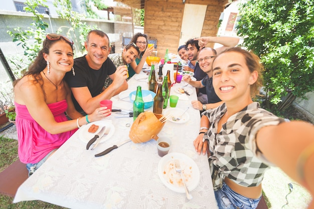 Groupe de personnes prenant selfie tout en déjeunant en plein air