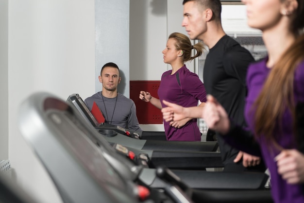 Groupe de personnes qui courent sur des tapis roulants dans la salle de sport