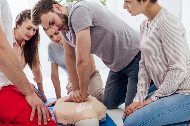 Photo groupe de personnes regardant un homme effectuant la rcr sur un mannequin pendant la formation aux premiers secours