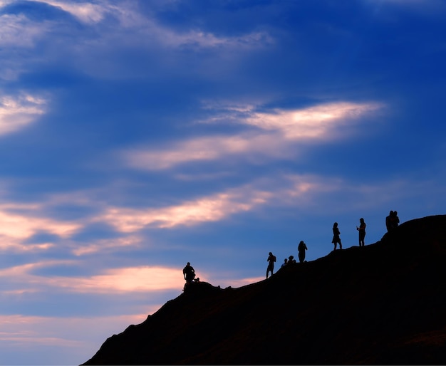 Groupe de personnes rencontrant le coucher du soleil sur le fond de la colline