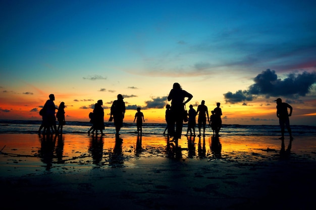 Photo un groupe de personnes se tient sur une plage au coucher du soleil.