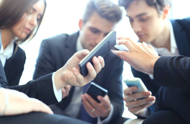 Groupe de personnes utilisant des téléphones intelligents assis à la réunion.