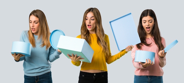 Groupe de personnes avec des vêtements colorés, tenant une boîte-cadeau dans les mains sur un fond coloré