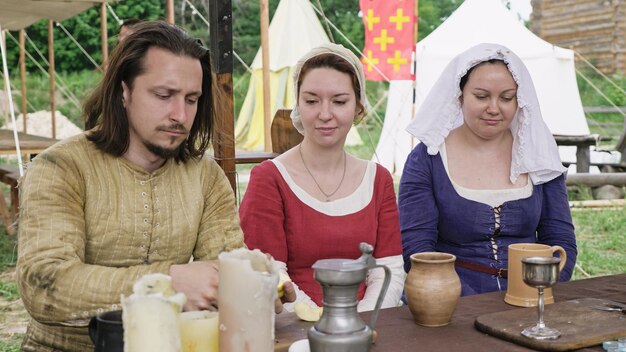 Groupe de personnes vêtues de vêtements médiévaux passant du temps ensemble assis à table