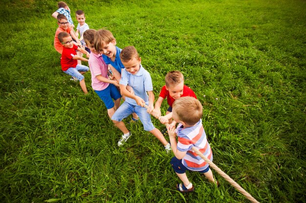 Le groupe de petits garçons tire une corde dans le parc