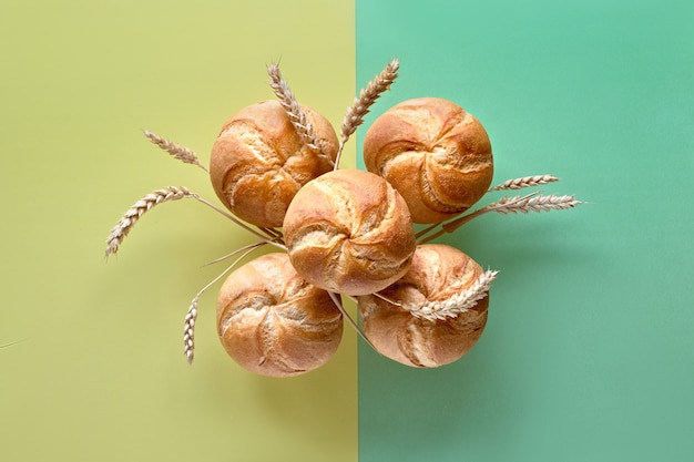 Groupe de petits pains croustillants ronds avec des épis de blé sur du papier de couleur jaune-vert fendu