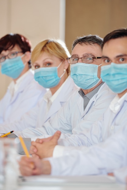 Groupe de pharmacologues en masques médicaux participant à une conférence sur les problèmes des services de santé