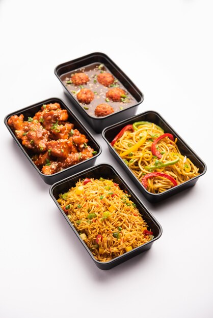 Groupe de plats indo-chinois livrés à domicile dans des emballages en plastique, des conteneurs ou des boîtes contenant des nouilles schezwan, du riz frit, du poulet au piment, de la manchourie et de la soupe.