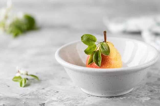 Un groupe de poires et de morceaux de poire sur une planche à découper blanche sur un fond de béton