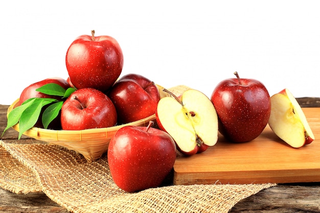 Groupe de pommes rouges fraîches sur une planche à découper en bois et dans un panier en bois.