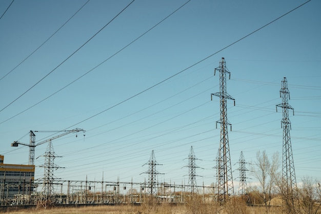 Groupe de poteaux avec des fils de haute tension sur ciel bleu.