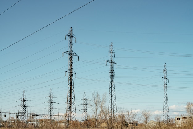 Groupe de poteaux avec des fils de haute tension sur scène de ciel bleu.