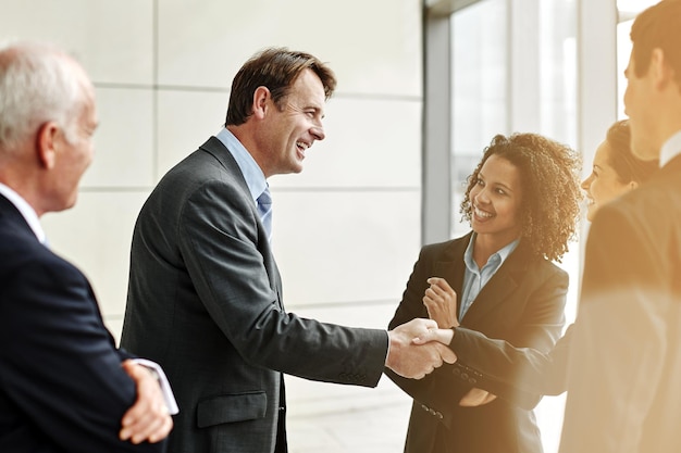 Groupe professionnel et négociation avec poignée de main pour accord avec conversation au bureau Hommes d'affaires et partenaire de bienvenue dans le hall pour une discussion sur le contrat dans l'entreprise