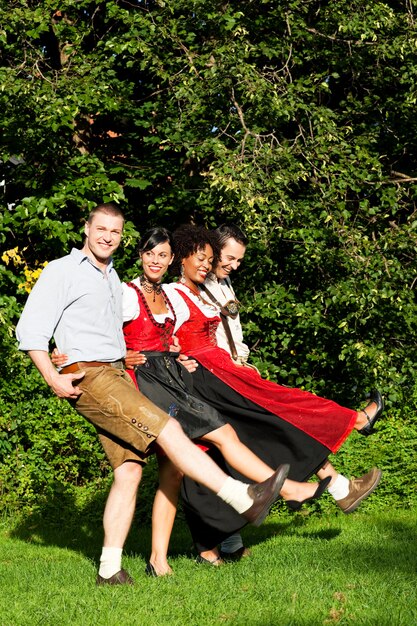 Groupe de quatre amis dansant des vêtements bavarois