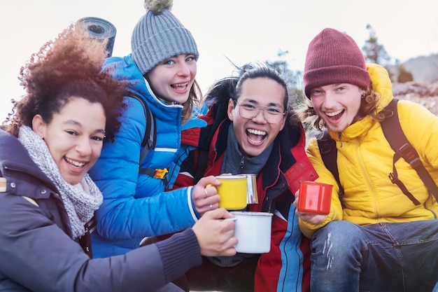 Groupe de randonneurs au sommet de la montagne prenant une pause pour boire et porter un toast Des amis heureux prennent un selfie Des personnes multiethniques ayant une journée de trekking ensemble