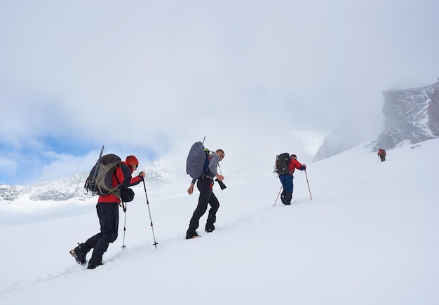 Groupe de randonneurs escaladant la colline couverte de neige