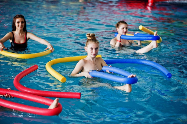 Groupe de remise en forme de filles faisant des exercices d'aérobic dans la piscine d'un parc aquatique.