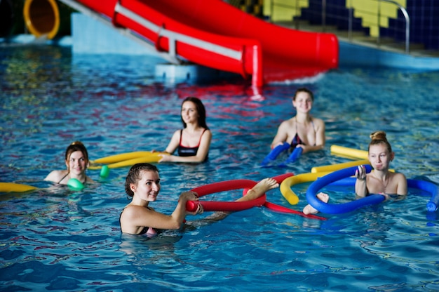 Groupe de remise en forme de filles faisant des exercices d'aérobic dans la piscine d'un parc aquatique.