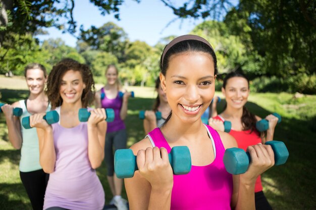 Groupe de remise en forme soulevant des poids de la main dans le parc