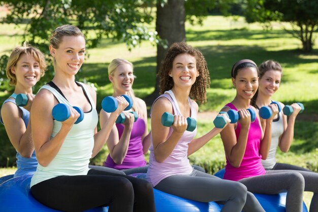 Groupe de remise en forme soulevant des poids de la main dans le parc