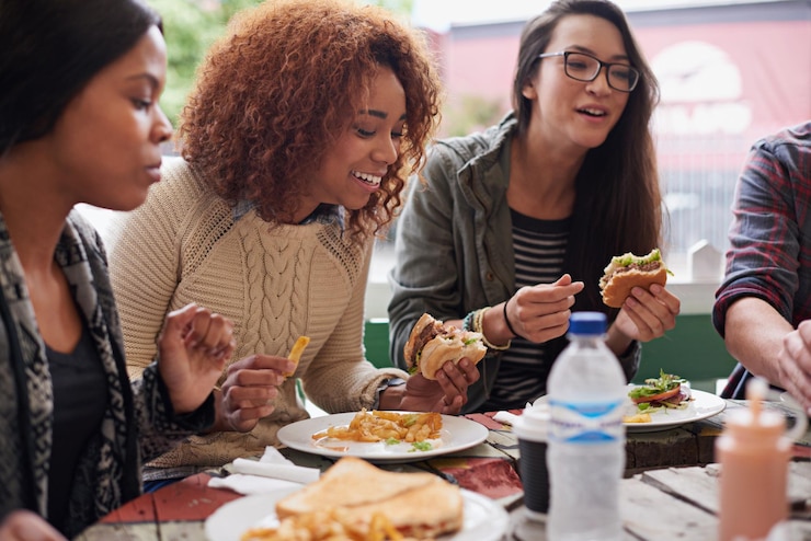 Photo groupe de restaurant et d'amis mangeant rassemblement social et réunion avec conversation et bonheur diversité femmes et étudiants en pause nourriture rapide et collation avec déjeuner et sourire avec discussion