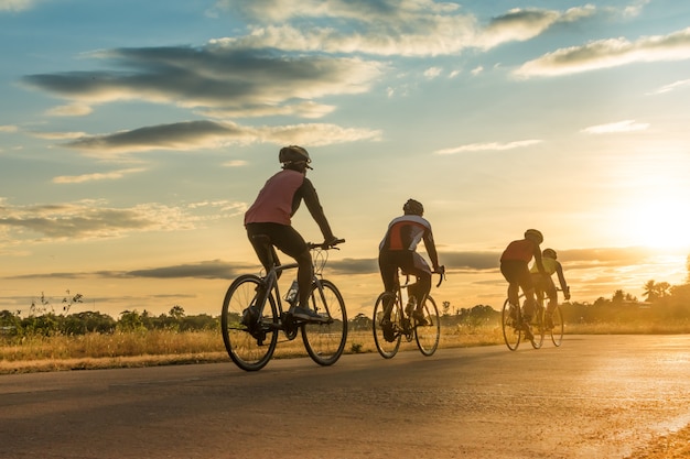 Groupe de silhouette d&#39;hommes à vélo au coucher du soleil.