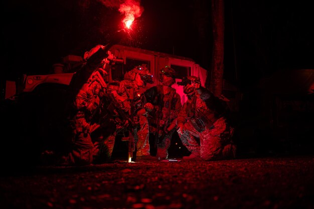 Un groupe de soldats en uniforme de camouflage tient des armes avec des missions de patrouille la nuit.