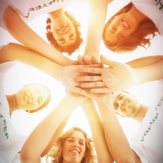 Photo groupe souriant de bénévoles empilant les mains