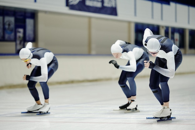 Groupe de sportifs en forme en uniforme participant à une course de patinage de vitesse sur piste courte