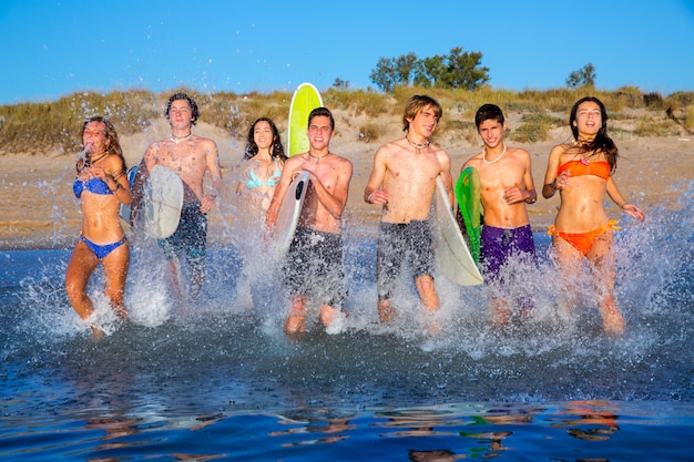 Groupe de surfeurs ado jouant sur la plage