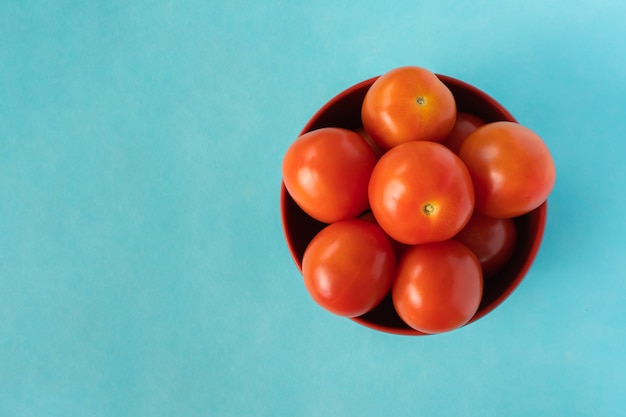 Groupe de tomates fraîches dans le seau sur fond bleu. Vue de dessus gros plan stock photo