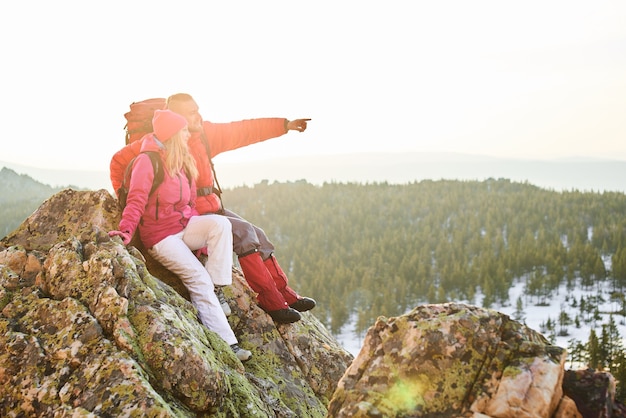 Un groupe de touristes composé d'une fille et d'un gars est assis au sommet d'une montagne