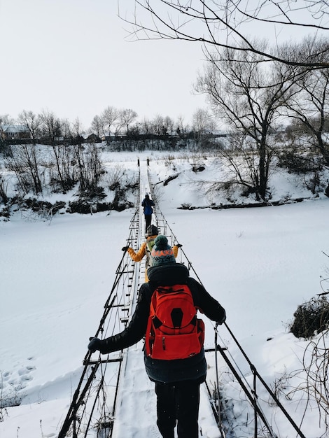 Un groupe de touristes de randonnée traverse le pont de la rivière Vue d'hiver