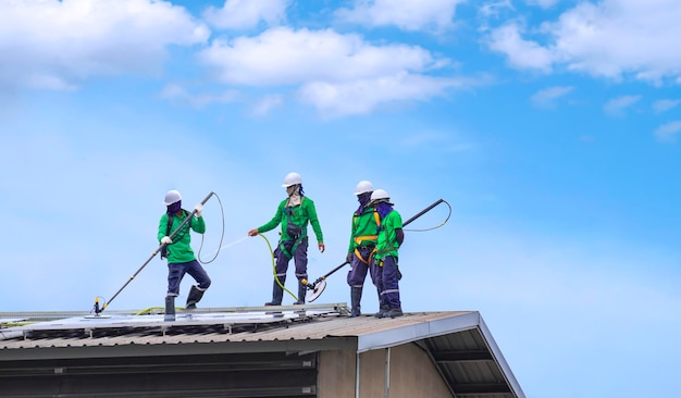 Un groupe de travailleurs des services de nettoyage nettoient des panneaux solaires sur le toit d'un bâtiment industriel