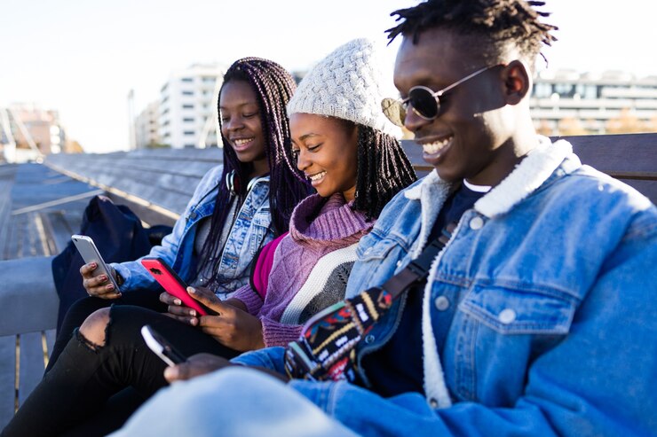 Groupe de trois amis utilisant un téléphone portable dans la rue.