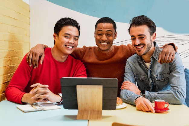 Groupe de trois jeunes étudiants masculins et amis assis dans un café assis à table