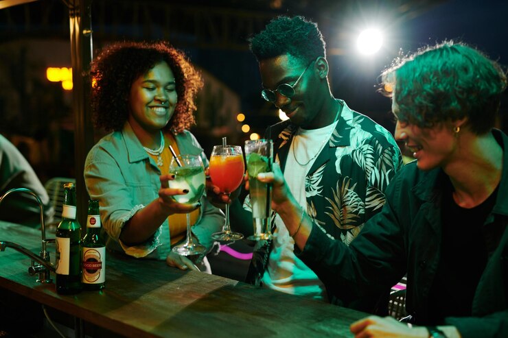 Groupe de trois jeunes gens interculturels heureux qui trinquent avec des cocktails