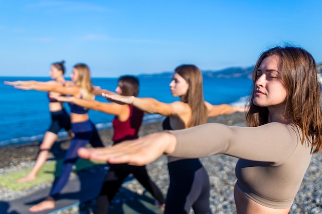 Groupe d'unité de femmes pratiquant le yoga sur la plage de rhe le matin