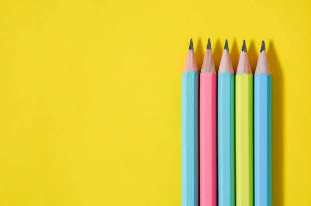 Groupe de la vue de dessus des crayons de couleur pastel en bois sur fond de papier jaune