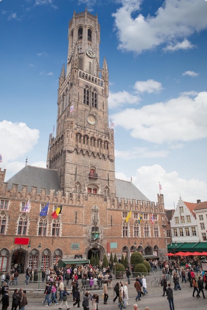 Des groupes de personnes bénéficiant de musiciens de rue dans la place Markt avec le Belfort comme surface