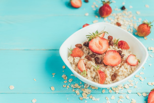 Gruau aux fraises fraîches et raisins secs sur fond bleu, plat